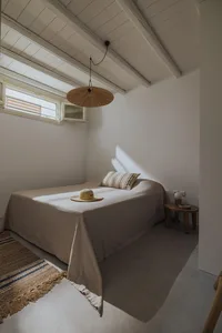 Minimalist bedroom with a side table, a bed with a fabric cover, and a textured rug