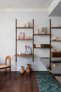 Minimalist floating shelves displaying various ceramic objects and books in a simple, modern interior design setting.