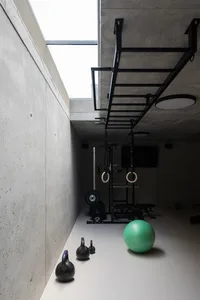 Concrete-walled minimalist gym with exercise equipment and a green exercise ball on the floor.