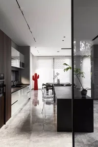 Modern kitchen with marble countertops and dining area with concrete floor and plants.