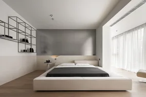 A spacious, minimalist bedroom with a large bed, modern lighting, and a sleek, gray accent wall.