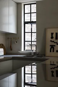 Modern minimalist kitchen featuring a concrete countertop and flooring, with a sleek stainless steel sink and a large window 