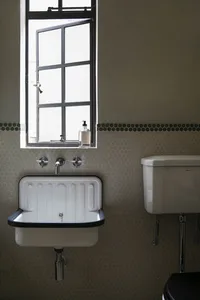 A modern bathroom with a white ceramic sink and a white ceramic toilet tank.
