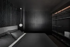 A minimalist black bedroom with wooden walls and a grey bed.