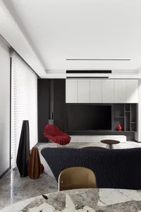A modern living room featuring a textured black couch, a sleek black chair, and a marble floor. Modern design elements includ