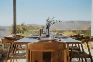 Outdoor dining area with a wooden table and chairs, set for a meal with a scenic mountain view.