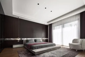 A modern bedroom featuring a dark accent wall, concrete flooring, and a comfortable bed with grey bedding.