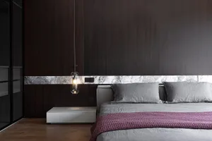 A minimalist bedroom with wooden walls, a grey bed, and a purple throw blanket.