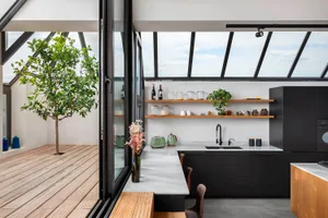Modern industrial-style kitchen with wooden countertops, metal cabinets, and glass shelving.