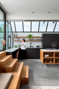 A modern kitchen featuring a combination of marble countertops, wooden cabinetry, and concrete flooring.