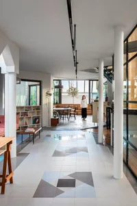 A contemporary living room with concrete floor tiles, industrial-style furniture, and large windows.