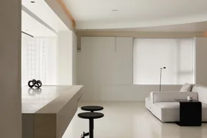 A modern living room with minimalist decor and neutral color palette, featuring a sleek sofa and a small black side table.