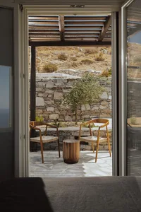 A terrace with stone walls and wooden furniture, featuring a view of the surrounding landscape.