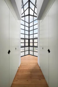 A modern, light-filled hallway with a glass ceiling and wooden floor.