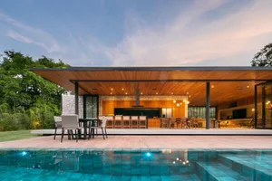 Modern residential outdoor kitchen featuring wood, stone, and glass materials.