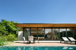 Modern residential exterior featuring glass, wood, and concrete materials.