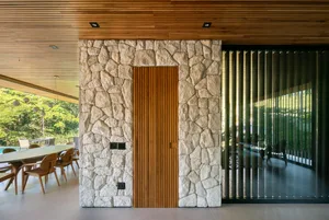 A modern doorway featuring a wooden door and stone wall.