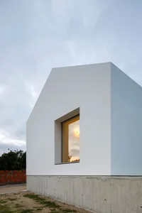 A minimalist concrete building with a white exterior and a single rectangular window.