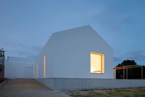 A modern house with a white exterior, featuring concrete and glass materials.
