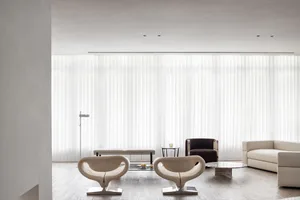 Modern living room with minimalist design, featuring white fabric furniture, glass table, and metal accents.