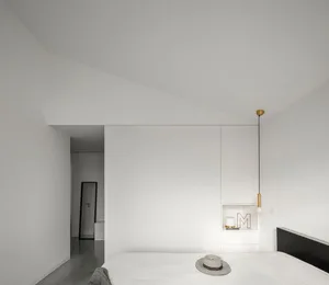 Modern minimalist bedroom with white walls, concrete floor, and a black and white striped hat on the bed.