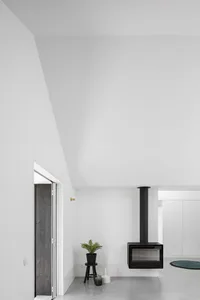 A minimalist living room featuring a modern concrete fireplace, tall ceiling, and open space.
