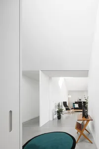 Minimalist living room with concrete walls, glass elements, and black and white furniture.