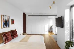 A modern, minimalist bedroom with a white bed, wooden floor, and minimalist decor.