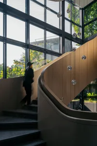 A modern, industrial-style staircase featuring large glass panels and a wooden handrail.