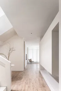 Modern minimalist house with white interior featuring wooden flooring, concrete walls, and glass elements.