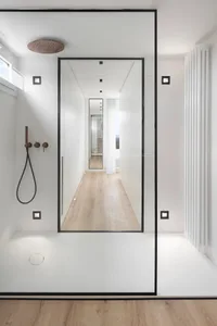 A minimalist bathroom with white walls and a glass shower enclosure.