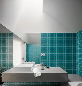 Modern bathroom featuring teal ceramic tiles and a concrete countertop.