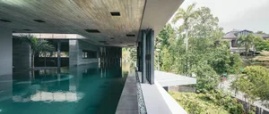 Modern house with concrete deck surrounded by lush greenery and palm trees.