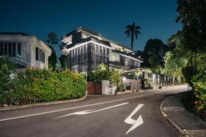 A modern house exterior at night with metal cladding, glass panels, and concrete materials.
