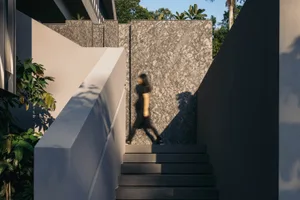 A modern interior space featuring textured concrete walls and stairs with a person walking.