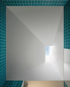 Interior with white walls and teal tiles on the ceiling and walls, featuring a skylight.