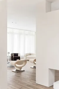 A modern living room featuring sleek, curved furniture and a wooden floor, with a focus on minimalist design elements.