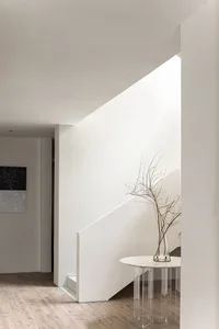 Modern living room with glass walls and floor-to-ceiling windows, featuring minimalist design and contemporary aesthetic.