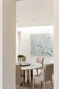 Modern, minimalist dining room with a round marble table and upholstered leather chairs.