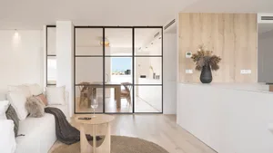 A modern minimalist living room with white furniture, glass walls, and wood accents.