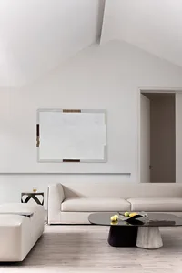 A modern minimalist living room with a minimalist sofa, abstract art, wooden floor, and geometric coffee table.
