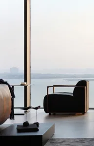 A minimalist living room with wood furniture, large windows, and a view of the cityscape.