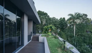 A modern residential exterior featuring a combination of wood, concrete, and greenery.
