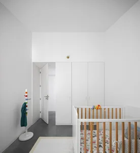 An image depicting a minimalist spa with white interior design, including a floor lamp, a wall mirror, and a white sofa.