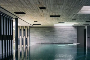 Modern indoor swimming pool with a concrete ceiling and walls.