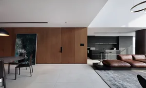 A modern minimalist living room featuring wooden walls, a leather couch, and metal accents.