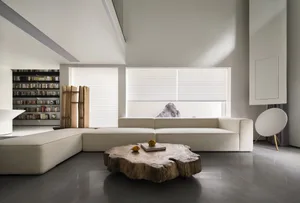 A minimalist living room featuring a white sectional sofa, wooden coffee table, and concrete floor.