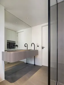 Modern minimalist bathroom with metallic counter and black taps.