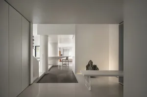 A minimalist interior design in white and black, featuring a concrete floor and walls with a single, modern table.