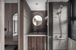 Modern minimalist bathroom with stone accents and a round mirror.